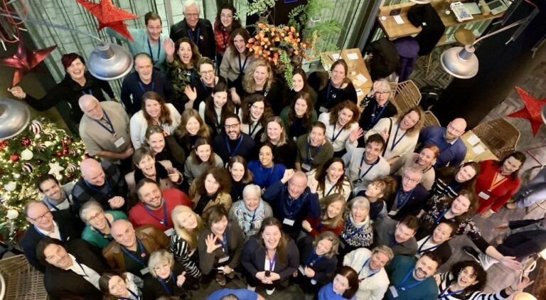 Didelė grupė renginio dalyvių žvelgia į viršų