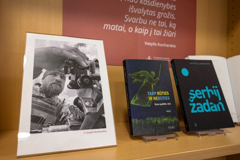 Fotografuojančio vyro nuotrauka ir pastatytos ukrainiečių rašytojų knygos bibliotekos lentynoje